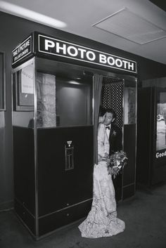 a bride and groom kissing in front of a photo booth