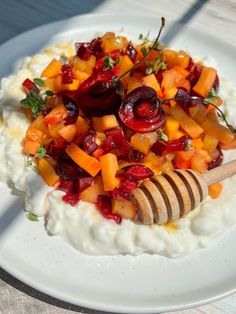 a white plate topped with mashed potatoes, fruit and a wooden utensil