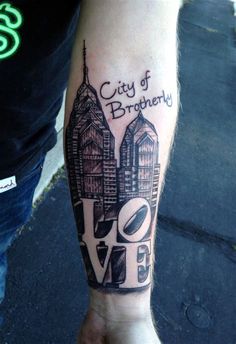 a person with a tattoo on their arm that says city of broughy and two buildings