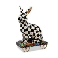 a black and white rabbit figurine sitting on top of a wooden cart with wheels