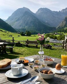 an outdoor table with food and drinks on it in the middle of a grassy field