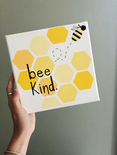 a hand holding up a bee kind card