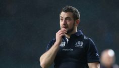 a rugby player covers his mouth as he stands in the rain