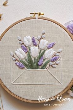 a close up of a embroidery on a hoop with flowers in an envelope and lavenders