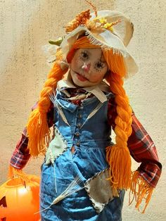 a scarecrow doll with orange hair and blue overalls