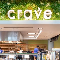 the interior of a restaurant with people standing in front of it and an overhead sign that says crave