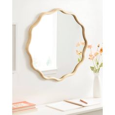 a mirror sitting on top of a white table next to a vase with flowers in it