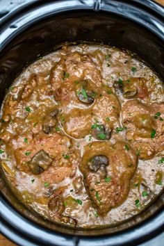 a slow cooker filled with meat and mushrooms