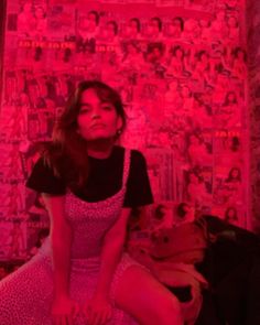 a woman sitting on top of a bed in front of a pink wall