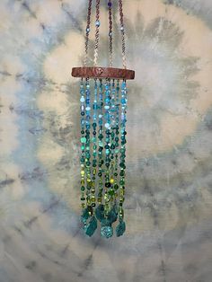 a wind chime hanging on the side of a tie - dyed wall with blue and green beads