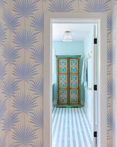 an open door leading into a hallway with blue and white wallpaper on the walls