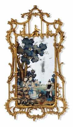 an ornate gold frame with a painting on the wall behind it and people sitting under a tree