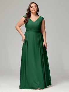 a woman in a long green dress with her hands on her hips, posing for the camera