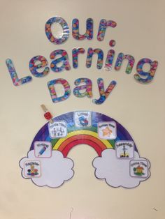 a sign that says, our learning day with rainbows and clouds on the wall