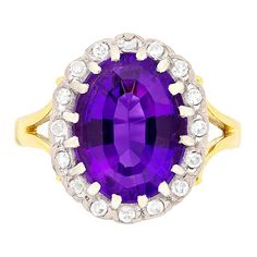 This beautiful dress ring features a natural amethyst in the centre. The colour is a beautiful deep purple and it weighs 4.50 carat. The halo of diamonds surrounding has a combined weight of 0.32 carat. They are 8-cut diamonds and they have been estimated as G in colour and VS in clarity. All the stones are claw set within platinum, whilst the gallery and band have been made in 18 carat yellow gold. Gemstone: Amethyst Stone Shape: Oval Carat Weight: 4.50 Metal: 18ct Yellow Gold, Platinum Age: 19 Classic Purple Diamond Ring With Halo Setting, Formal Purple Diamond Ring With Halo Setting, Heirloom Purple Diamond Ring For Formal Occasions, Purple Heirloom Diamond Ring For Formal Occasions, Formal Heirloom Purple Diamond Ring, Dress Ring, Dress Rings, Diamond Cluster, Amethyst Stone