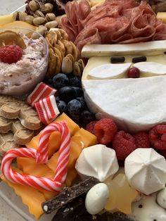 a platter filled with cheese, crackers, fruit and other food on top of it