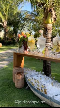 a table with glasses and bottles on it in the grass next to a palm tree