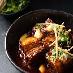 a close up of a bowl of food with meat and vegetables in it on a table