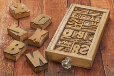 wooden letters and numbers are laid out on the floor next to a box with glass beads