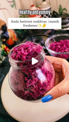 a person holding up a jar filled with red cabbage next to another bowl full of food