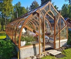 a house made out of wood and glass in the middle of a yard with lots of greenery