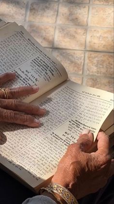 an old woman reading a book with her hands resting on the open book's pages