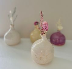 three vases with flowers in them sitting on a table next to each other,