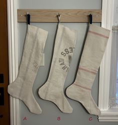 three stockings hanging from hooks in front of a door with the word ess written on them