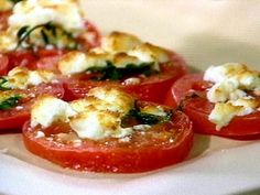 tomatoes stuffed with mozzarella cheese and spinach leaves on a white platter