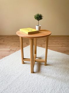 a small potted plant sitting on top of a wooden table next to a book