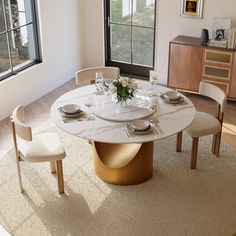 a dining room table with chairs and plates on it in front of a large window