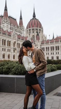 a man and woman kissing in front of a building