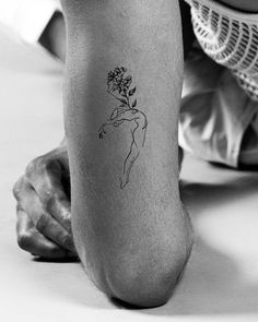 a woman with a flower tattoo on her leg is sitting and looking down at the ground