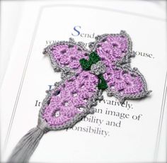 a crocheted butterfly brooch sitting on top of an open page of paper