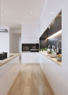 a modern kitchen with white cabinets and wood flooring on the walls, along with potted plants