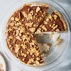 there is a chocolate pie with nuts on the top and one slice missing from it