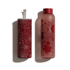 a red water bottle next to a pink and white container with flowers on it, against a white background