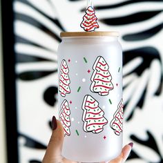 a hand holding up a white can with christmas trees on it