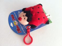 a red and black stuffed animal laying on top of a pair of scissors