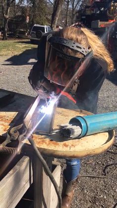 a woman welding something on top of a wooden table