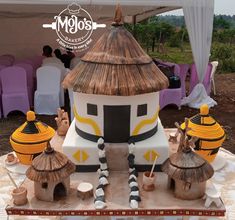 a cake made to look like a house with thatched roof and straw huts on top