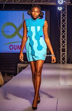 a model walks down the runway in a blue dress