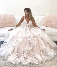 a woman is sitting on a couch wearing a wedding dress with white flowers and sheer tulle