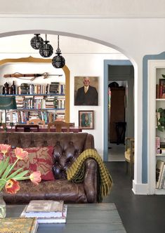 a living room filled with lots of furniture and bookshelves next to a doorway