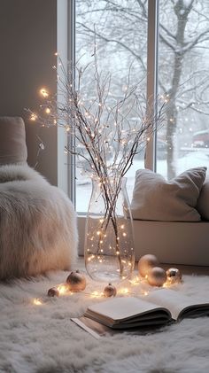 Cozy living room with a white fur rug, twinkling lights in a vase, warm-lit ornaments, and snow visible through a large Clear Glass Vases Decor Ideas, Winter Wonderland Living Room, Silver And White Christmas Decor, Wonderland Living Room, Warm Winter Aesthetic, Cozy White Christmas, Glass Vases Decor Ideas, Winter Wonderland Home Decor, White Fur Rug