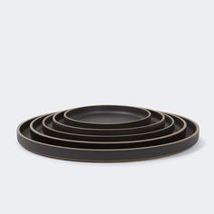 four black plates stacked on top of each other in front of a white background,