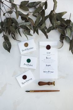 the wedding stationery is laid out on top of the table with some greenery