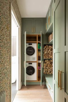 a washer and dryer in a green cabinet with wood stacked on the floor