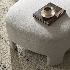 a cup of coffee sitting on top of a white ottoman