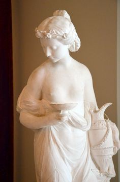 a statue of a woman holding a basket in her hands and wearing a white dress